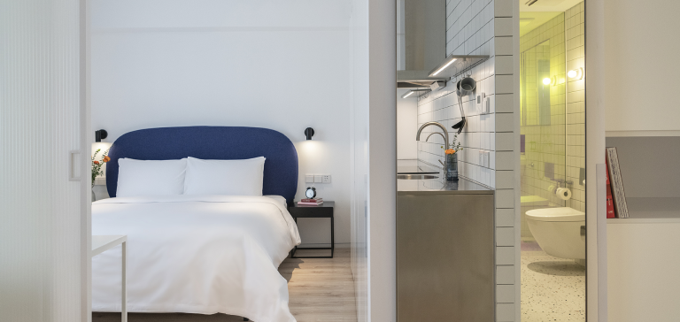 a bed with a blue headboard and a sink in a room